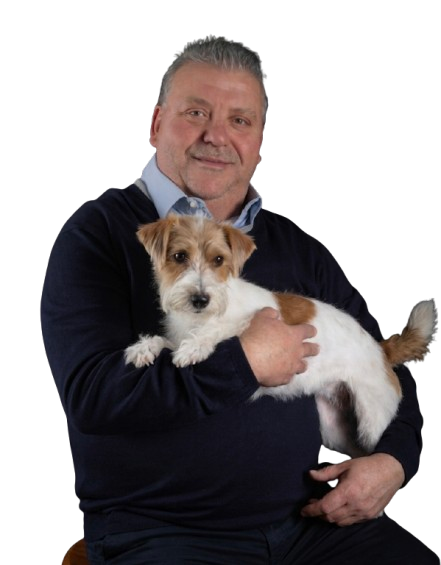 Man with glasses wearing a navy blue shirt and jeans holding a small white and brown dog.