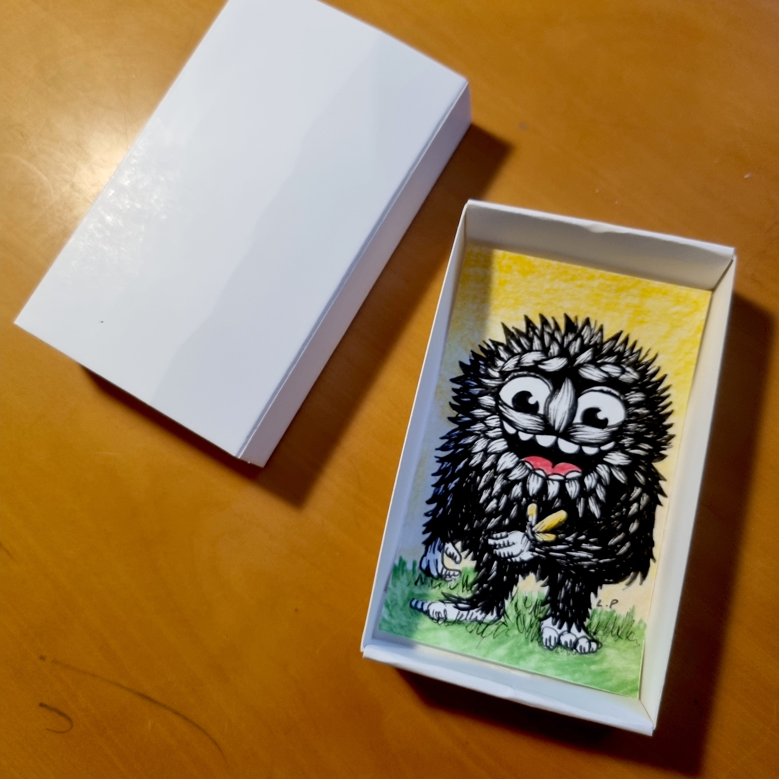 Cute drawing of a black monster in a white paper box.