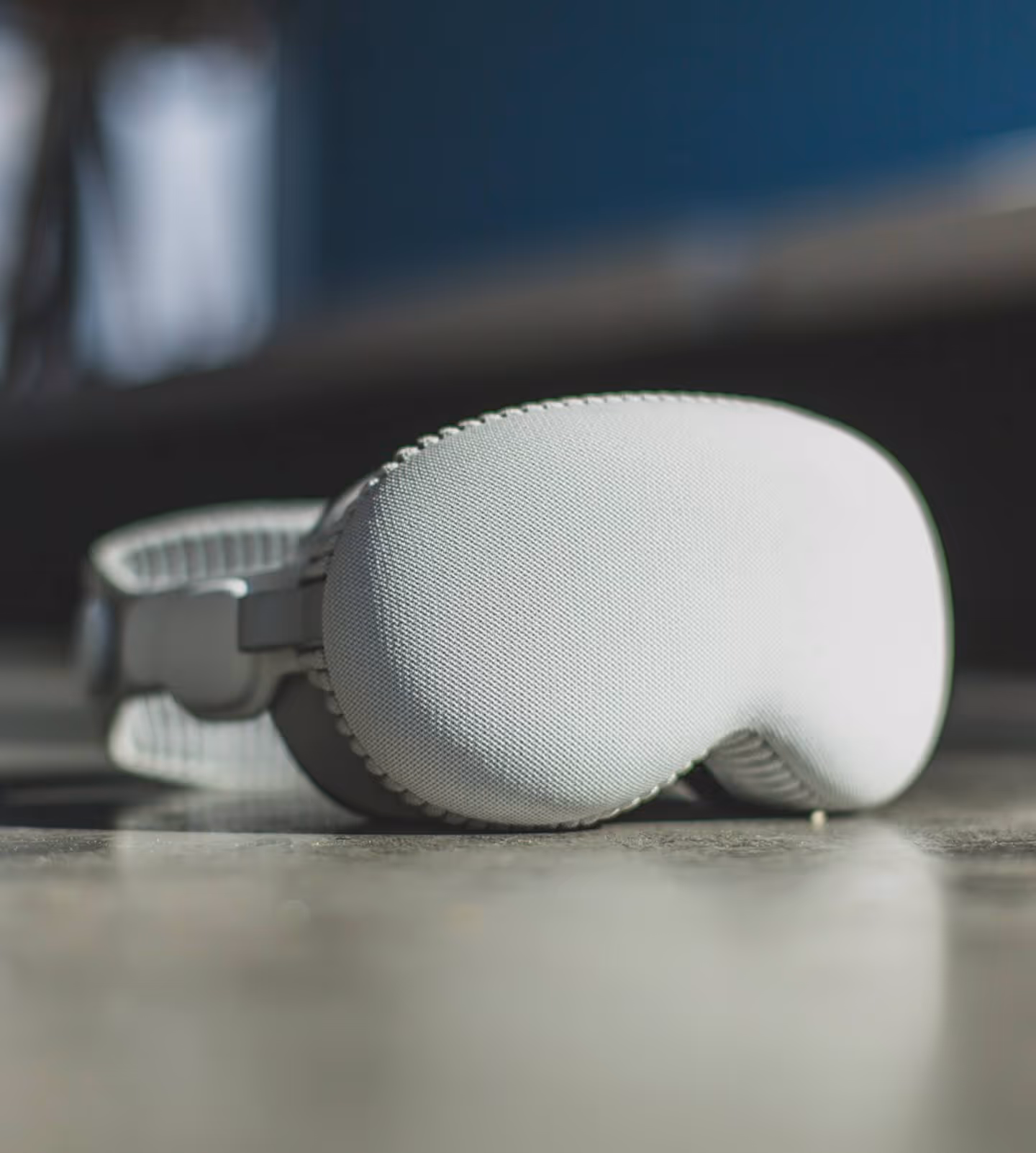 Close-up of a white textured sleep mask resting on a reflective surface with a blurred background.