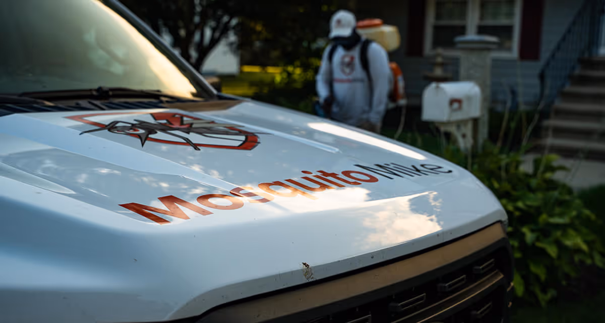 Mosquito Mike truck with pest technician performing spray treatment to fight against mosquitoes and ticks.