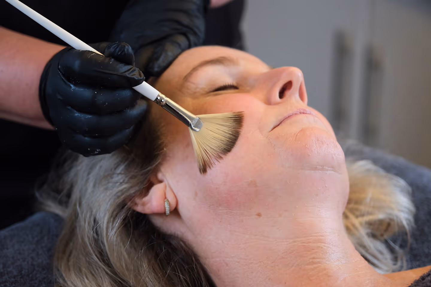 Vrouw ontvangt een professionele gezichtsbehandeling bij Essenzi Huidstudio