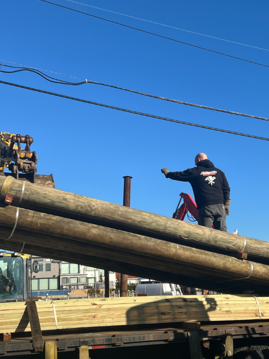 Atlantic Industries marine construction crew installing heavy timber pilings for residential dock and bulkhead system along a coastal canal.