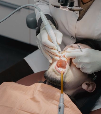 Medic stomatolog care efectuează o procedură dentară unui pacient în scaunul de dentist.