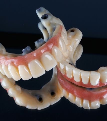 Modele detașabile de proteze dentare cu dinți artificiali și gingii roz pe fundal negru.