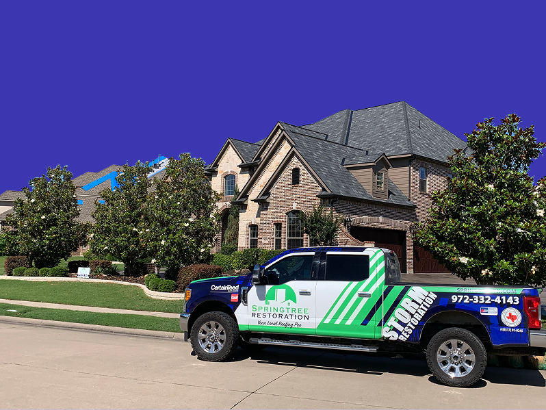 Pickup truck with SpringTree Restoration branding parked on a driveway in front of a large brick house with manicured trees.
