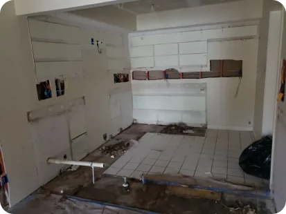 Room under renovation with partially tiled floor, exposed plumbing pipes, and unfinished walls.
