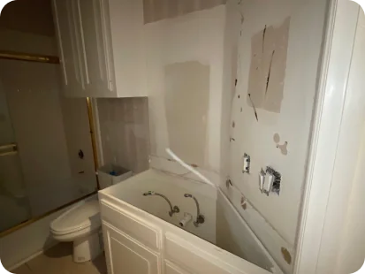 Bathroom under renovation with a bathtub, toilet, and unfinished walls with missing fixtures.