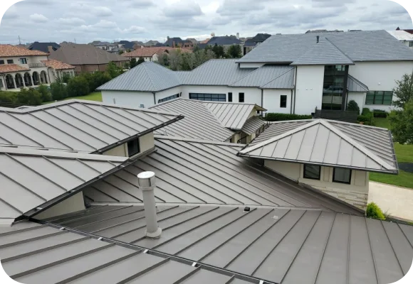 View of multiple connected modern metal rooftops with a cloudy sky and residential homes in the background.