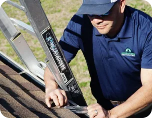 Man in a navy blue uniform and cap using a ladder to work on a roof.