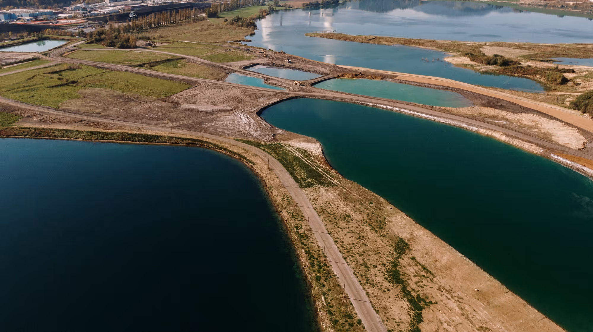 Aerial view of water treatment or retention ponds separated by dirt roads and patches of grassland.