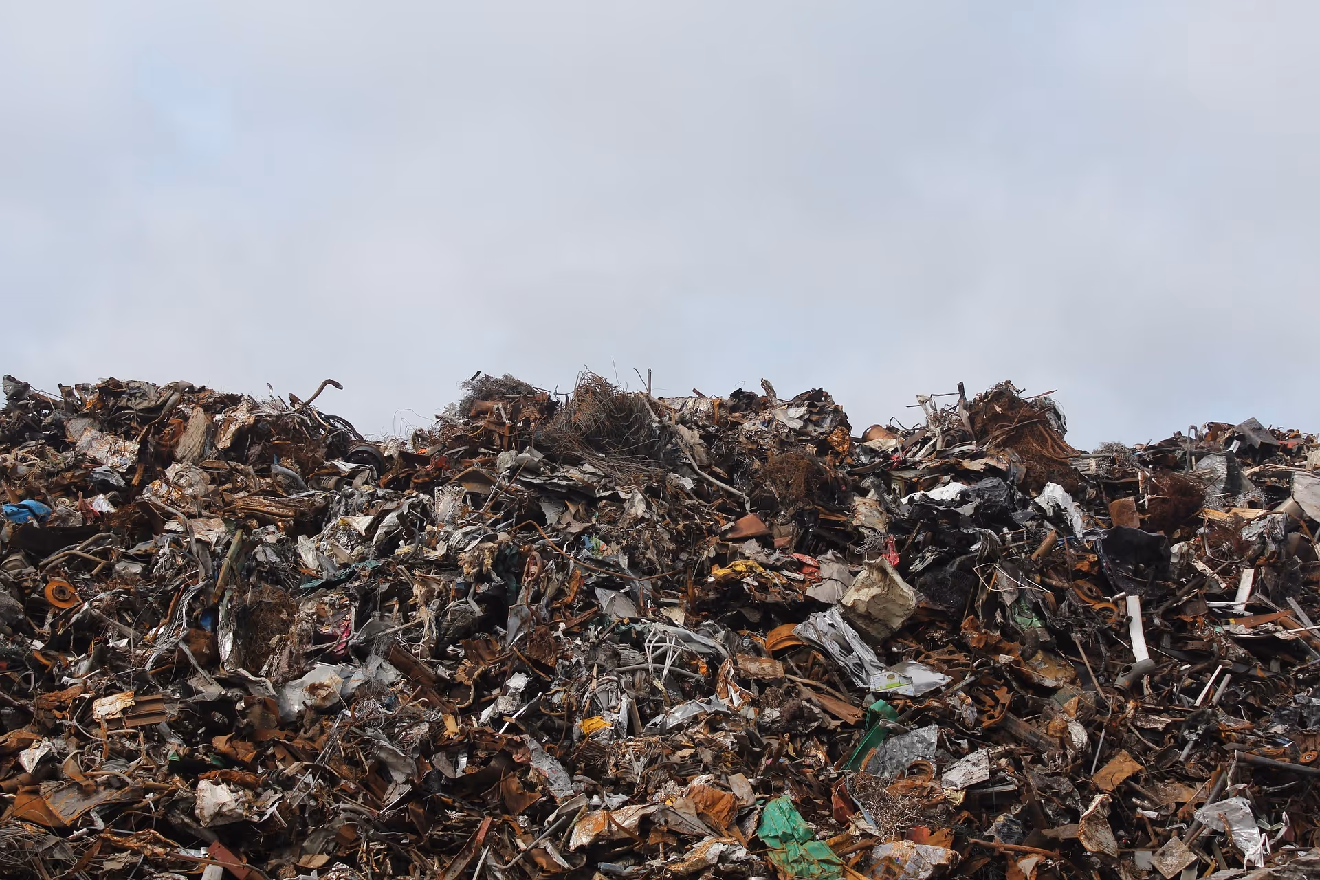 Large pile of scrap metal and debris against a cloudy sky background.