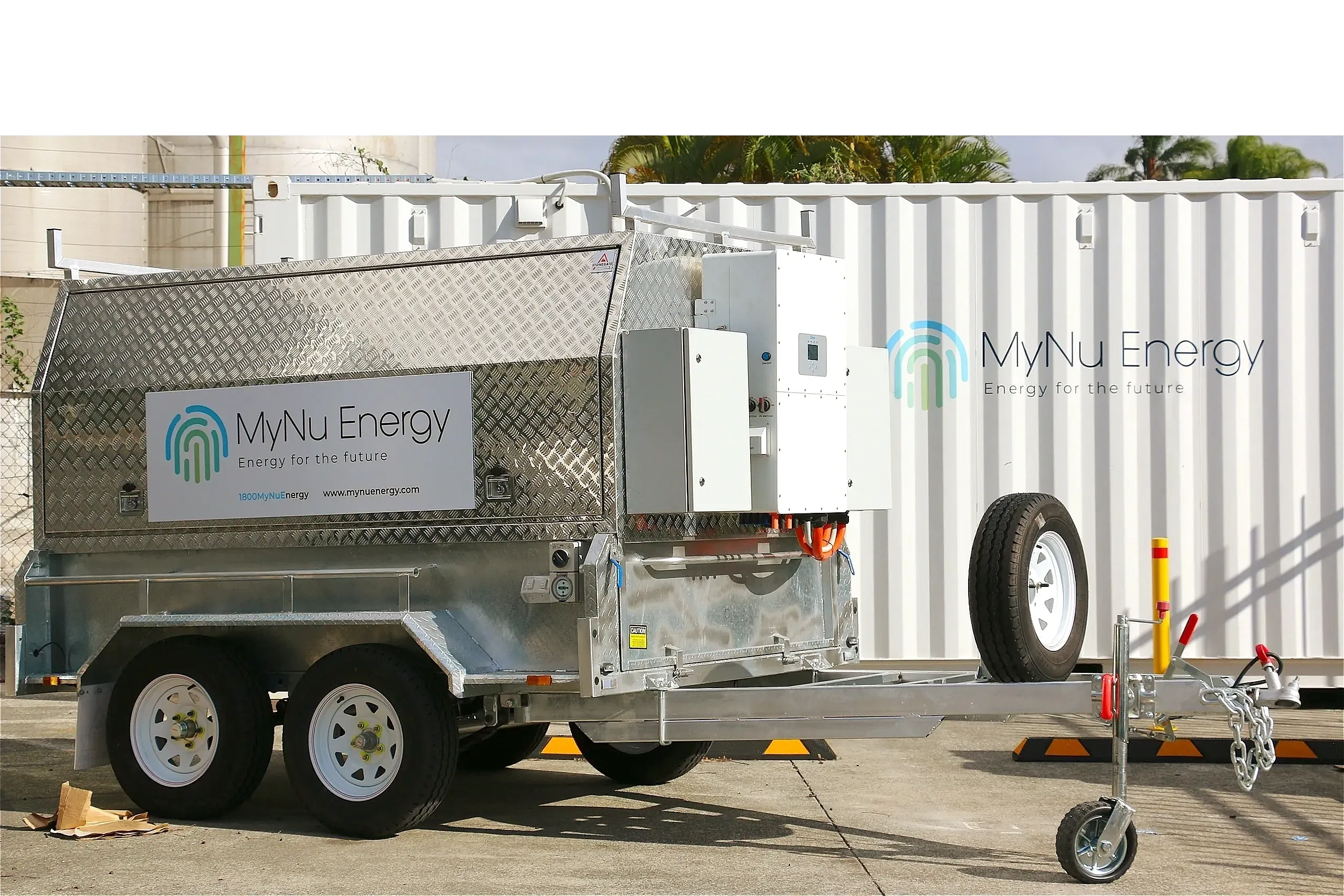Metal trailer with MyNu Energy logo and equipment parked in front of a white container.