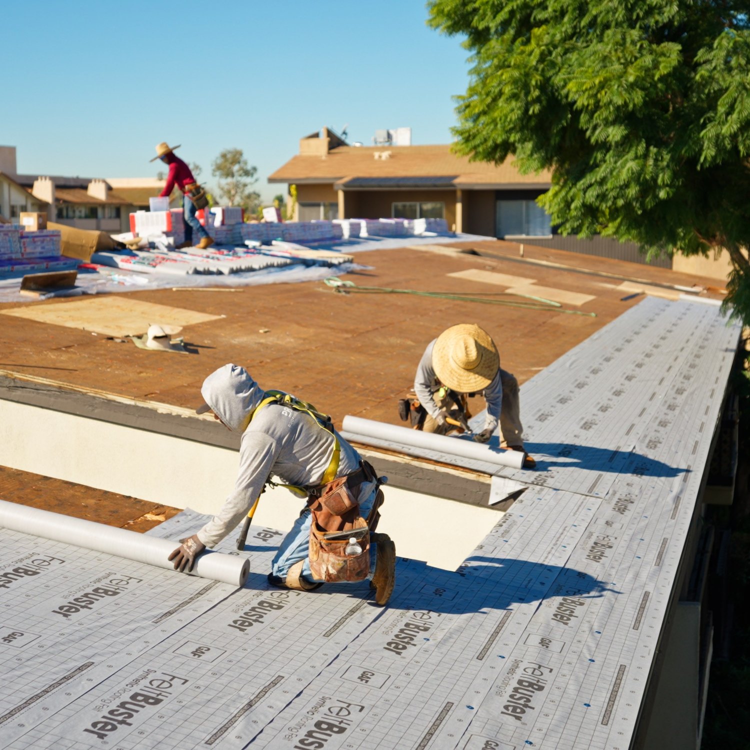 Merit Roofing crew installing GAF underlayment on an HOA building re-roof in Seal Beach