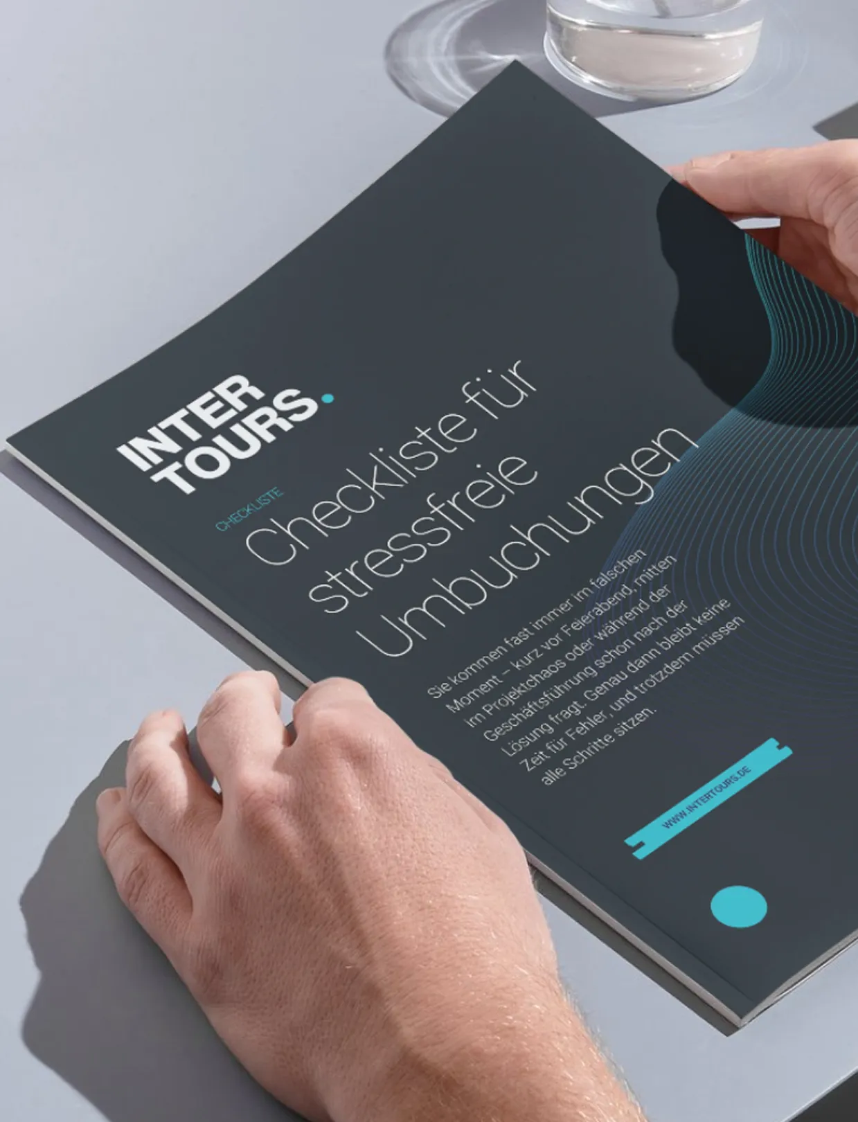 Zwei Hände halten eine Broschüre mit dem Titel „Checkliste für stressfreie Umbuchungen“ von INTERTOURS auf einem hellgrauen Tisch neben einem Glas Wasser.