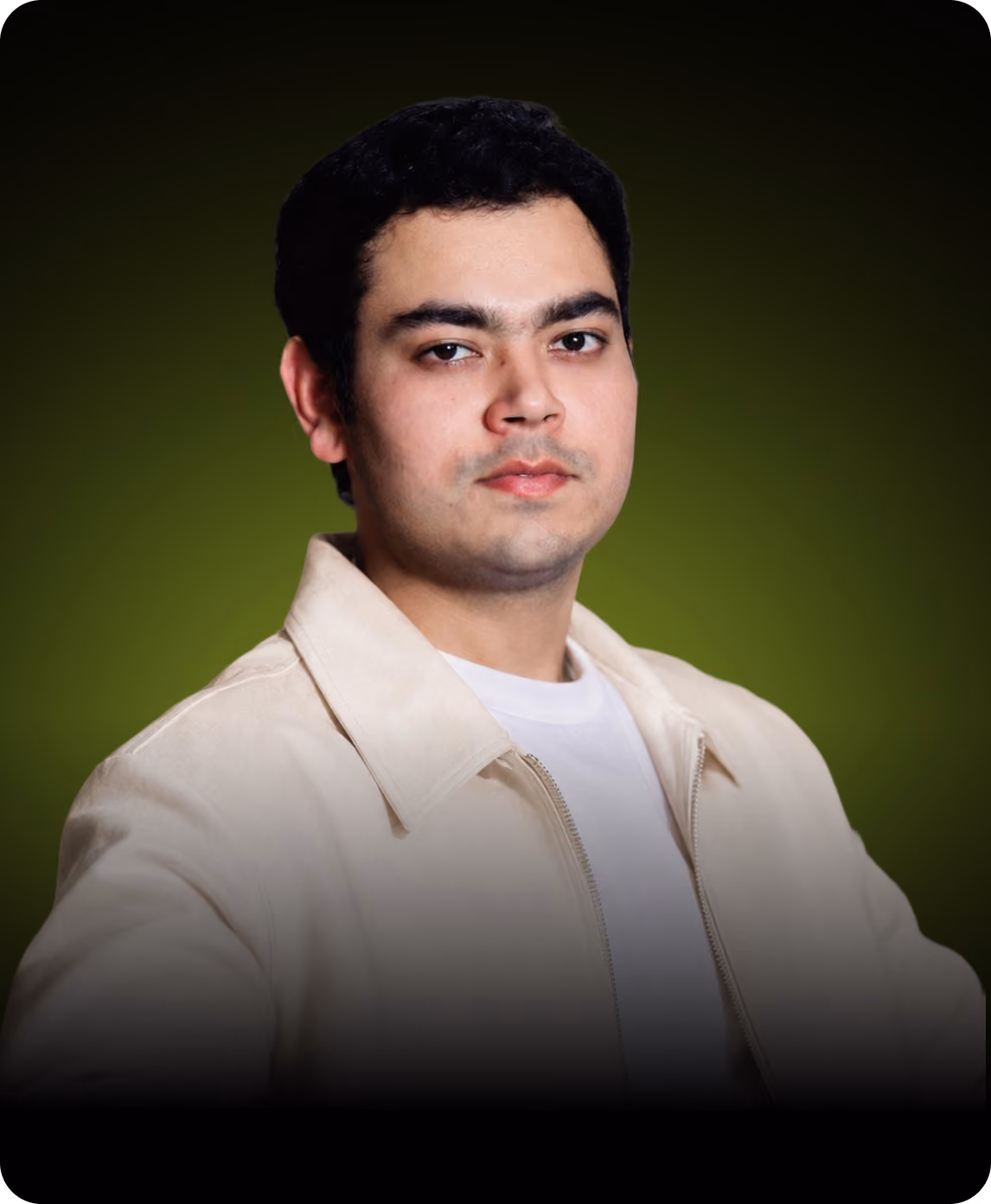 Portrait of a young man with short black hair wearing a light jacket and white shirt against green background.