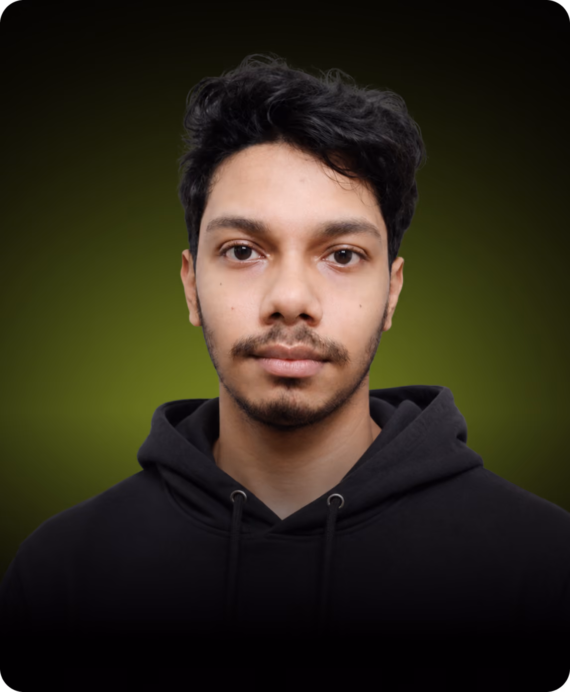 Young man with dark hair and slight beard wearing a black hoodie against a green background.
