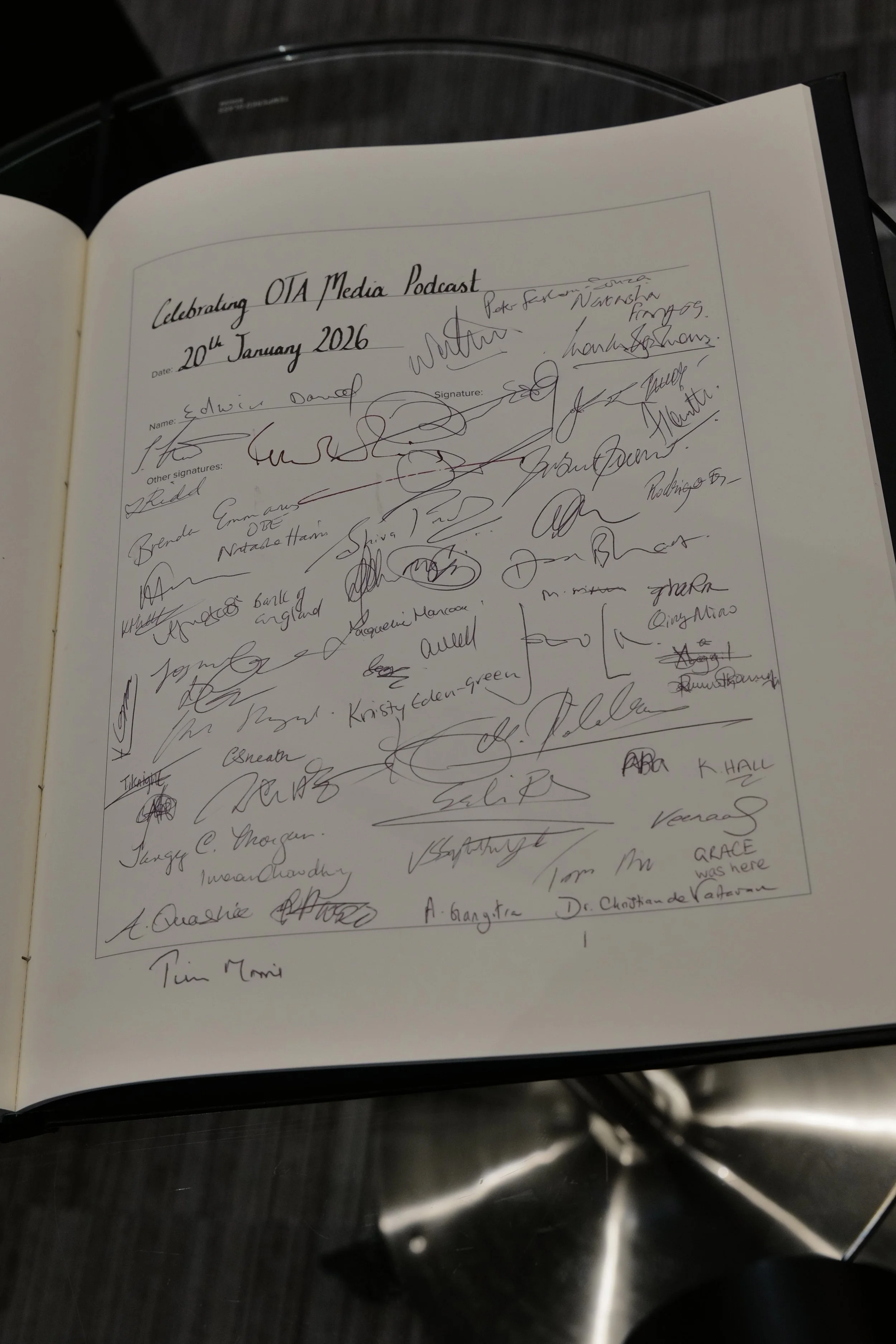 Open book page titled 'Celebrating OTA Media Podcast 20th January 2026' featuring numerous signatures in black ink.
