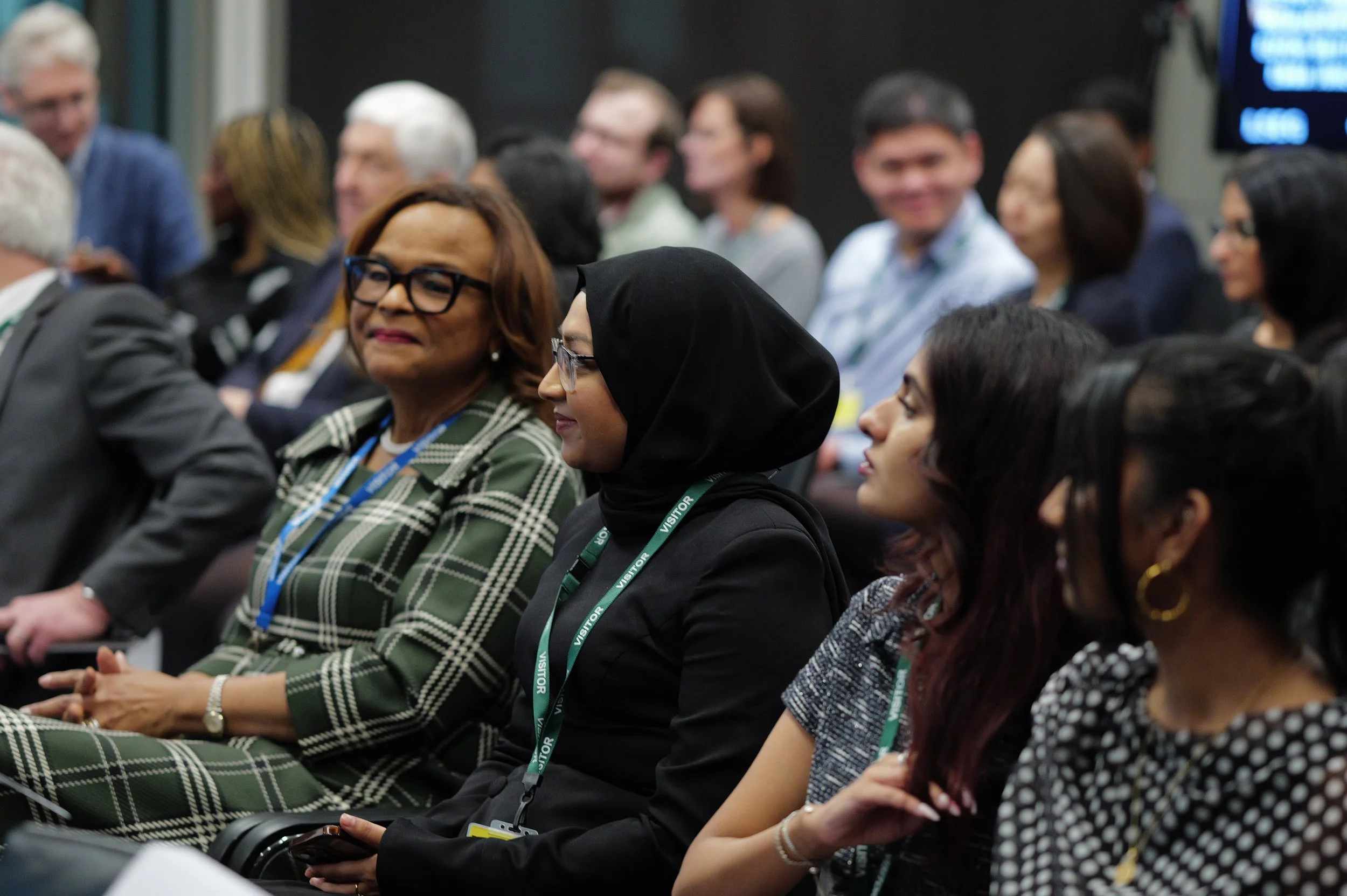Diverse group of adults seated attentively in a conference or seminar setting.