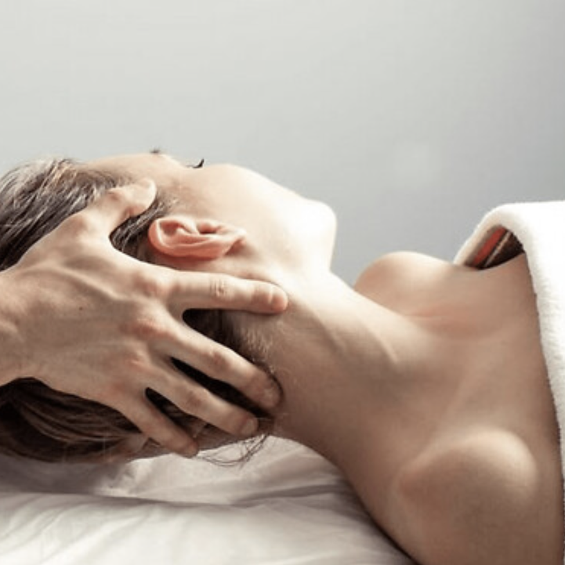 Therapeut geeft een ontspannende hoofdmassage aan een cliënt die op de massagetafel ligt bij Rustpunt