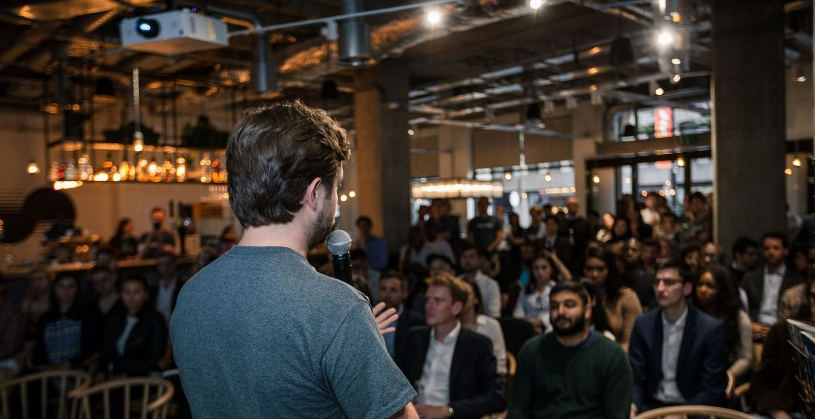 Man speaking to a seated crowd