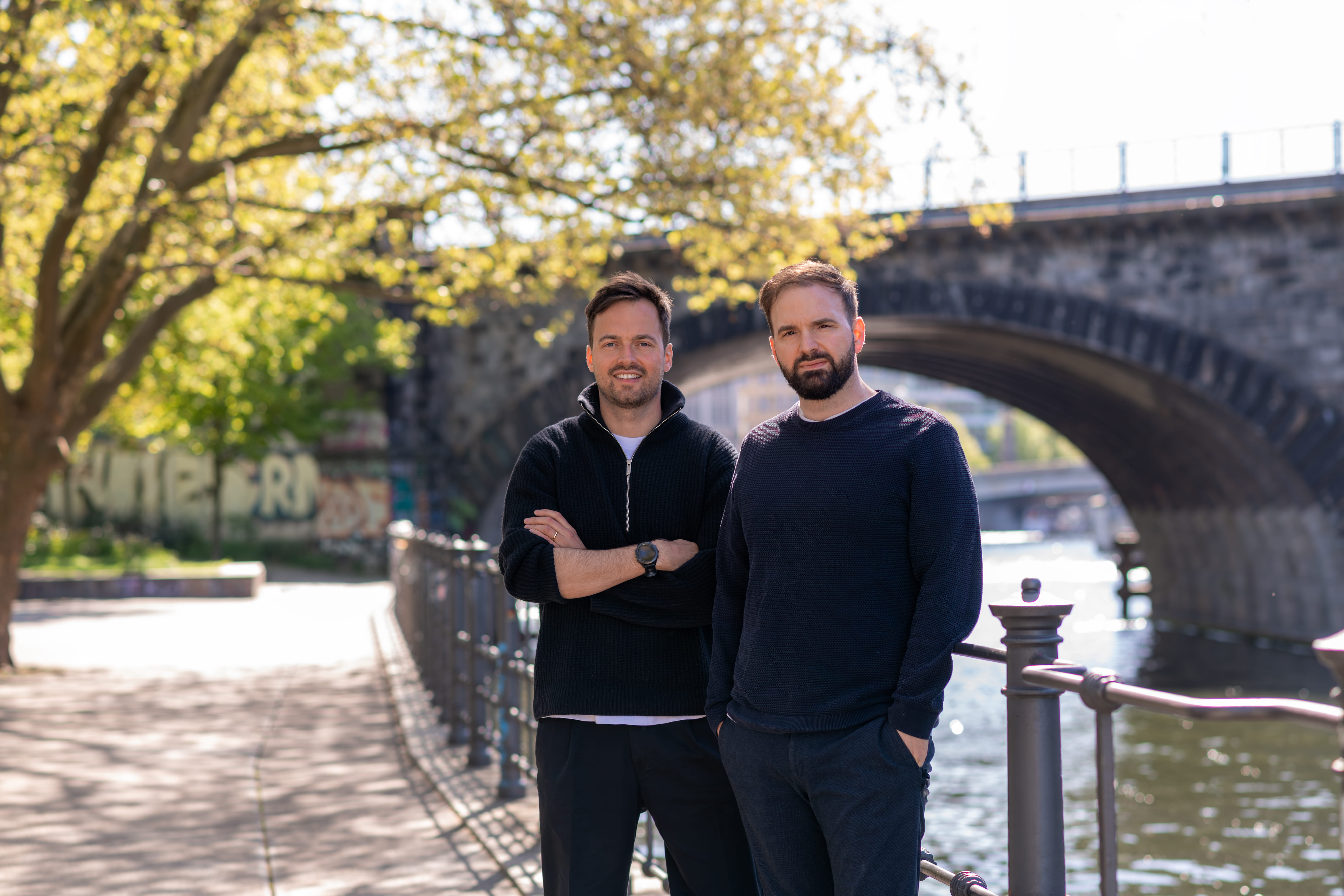 Two men, one in black shirt and one in blue, looking towards the camera