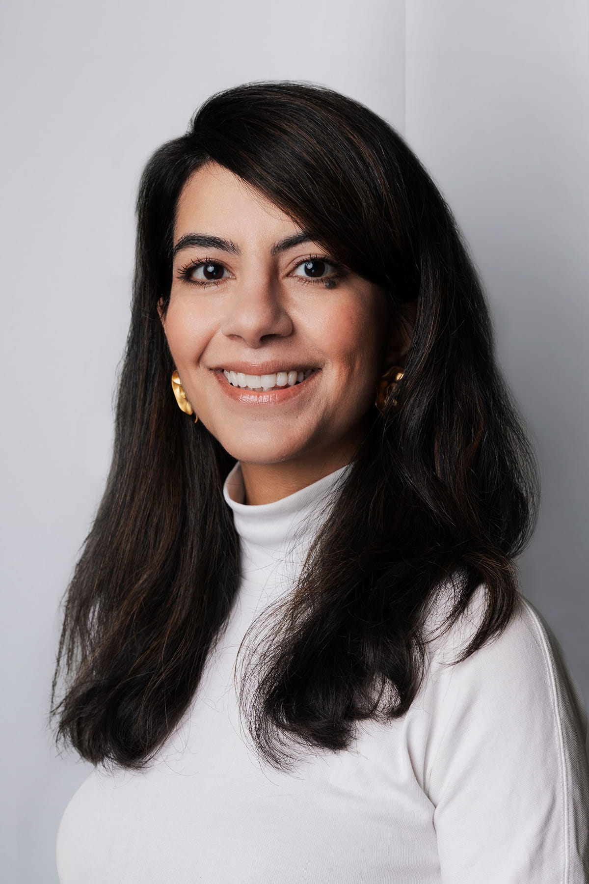 Portrait photo of a woman posed in front of a grey wall