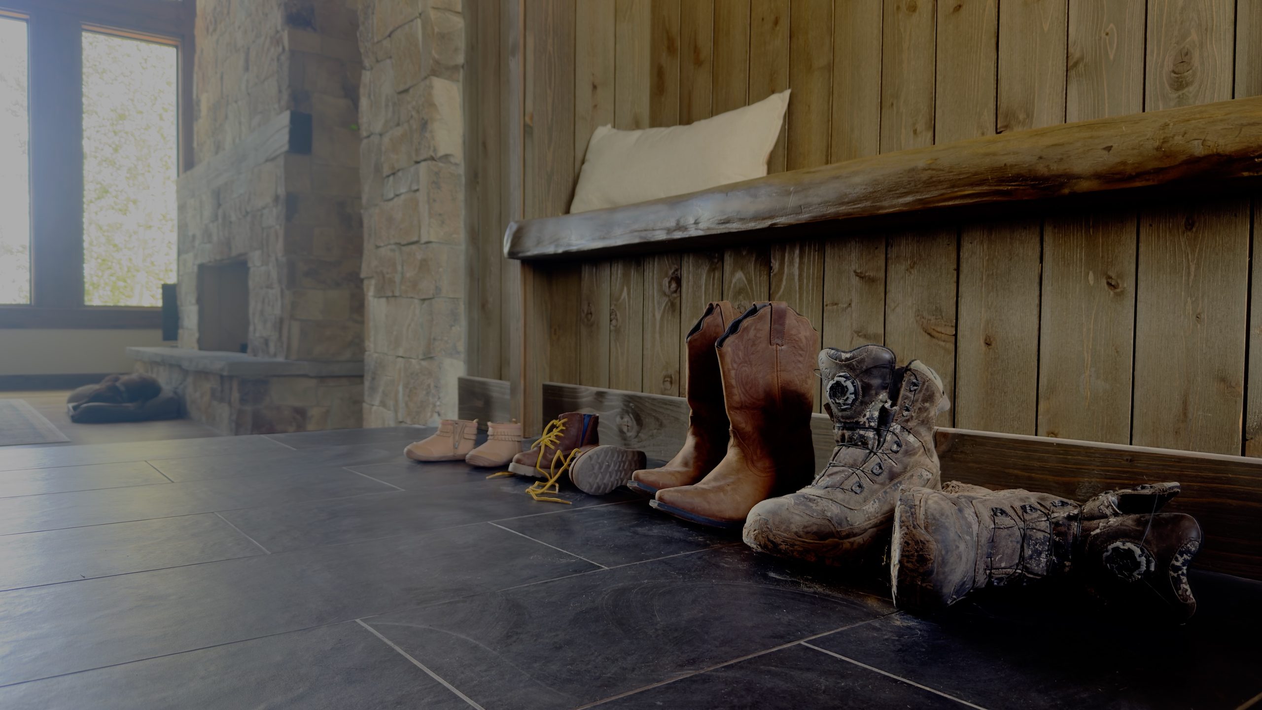 Boots and shoes lined up along the entry bench of a Hearthstone home