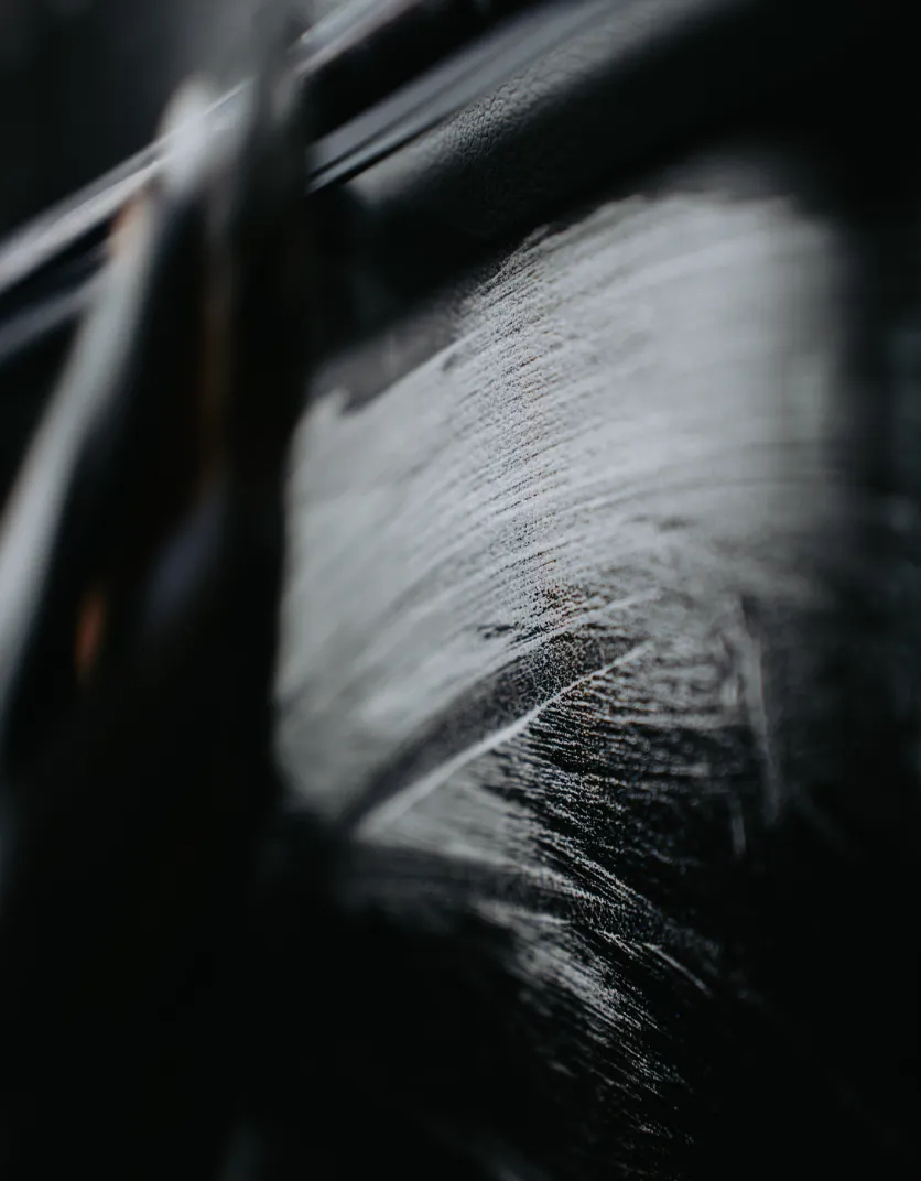 Close-up of a white brush stroke on a black textured surface, possibly leather.