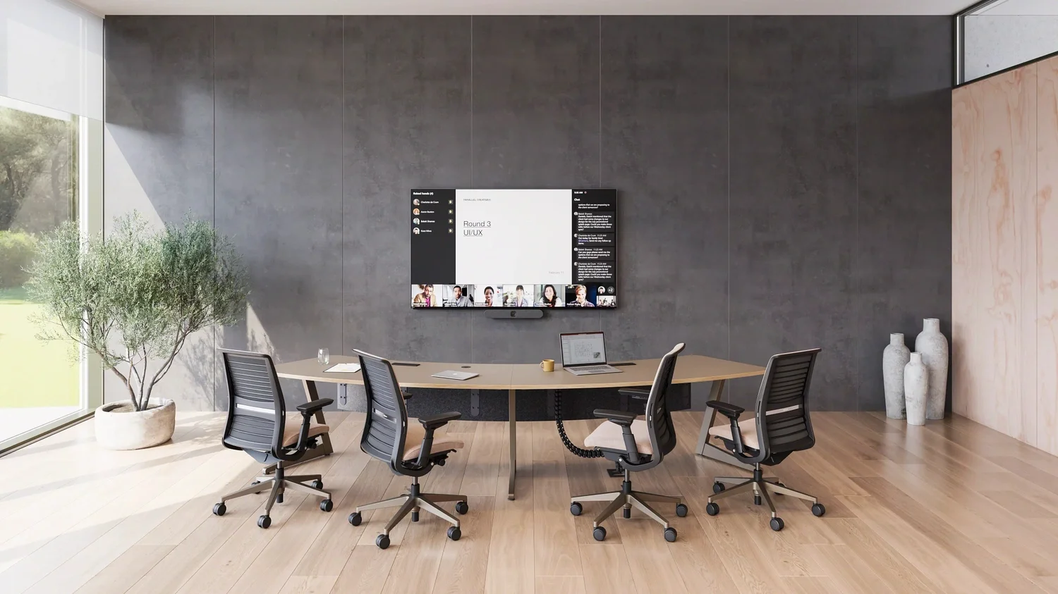Modern conference room with a wooden table, four office chairs, a wall-mounted screen showing a UI/UX meeting, and large windows allowing natural light in.