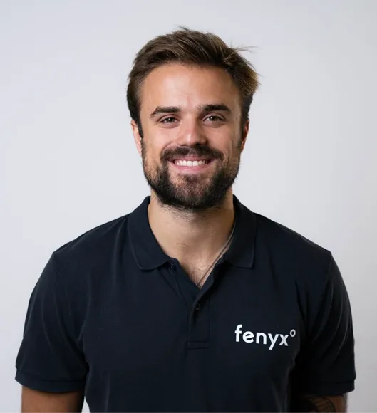 Smiling man with dark hair and beard wearing a black polo shirt with 'fenyx°' logo on the left chest.