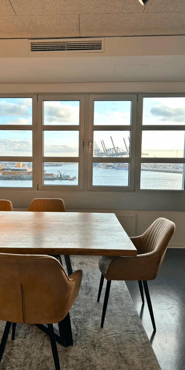 Heller Meetingraum mit großem Tisch und großen Fenstern