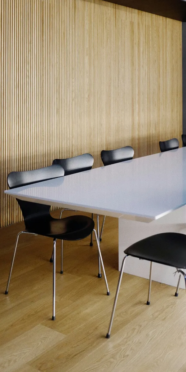 Besprechungstisch mit gepolsterten Stühlen vor Holzlamellenwan