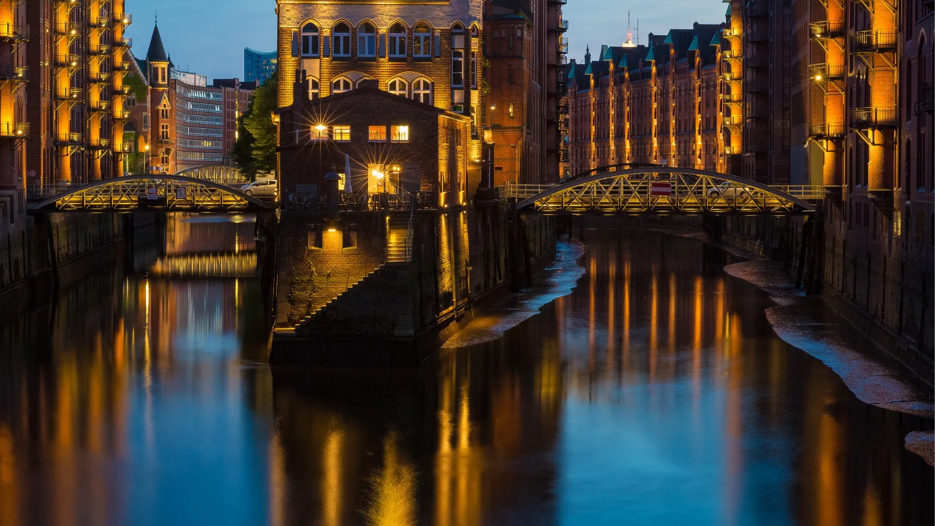 Abendaufnahme der beleuchteten Speicherstadt mit Kanälen und Brücken in Hamburg.