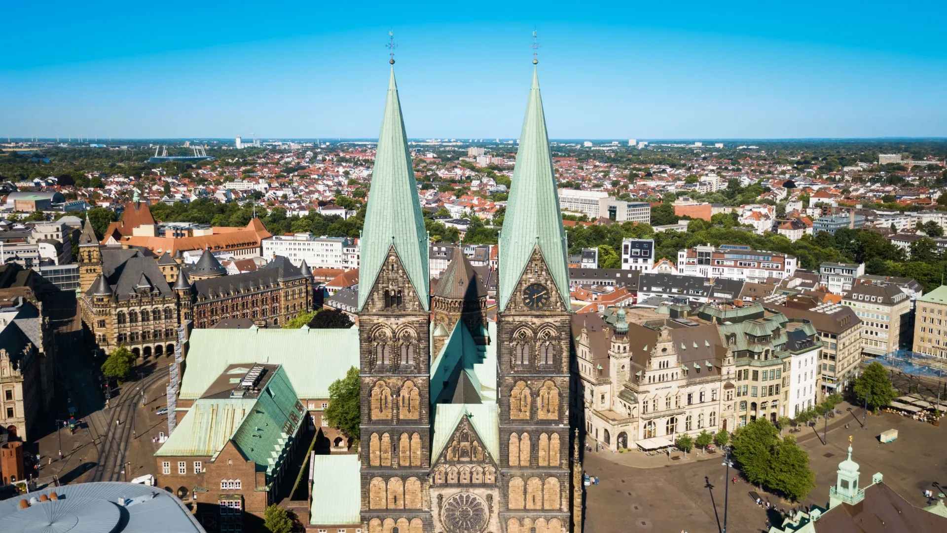 Luftaufnahme vom Bremer Dom mit seinen zwei spitzen Türmen und der umliegenden Stadt bei klarem Himmel.