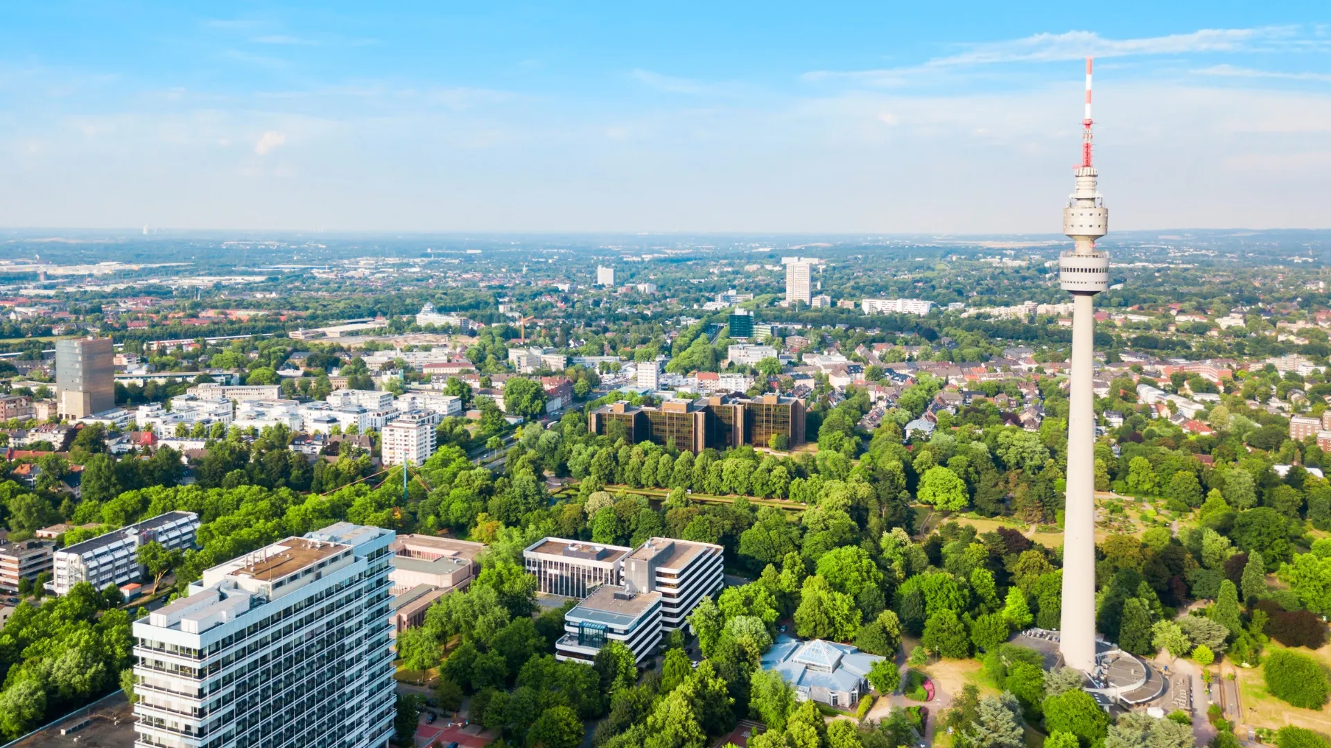 Luftaufnahme von Dortmund mit Fernsehturm und vielen grünen Bäumen in der Stadt.