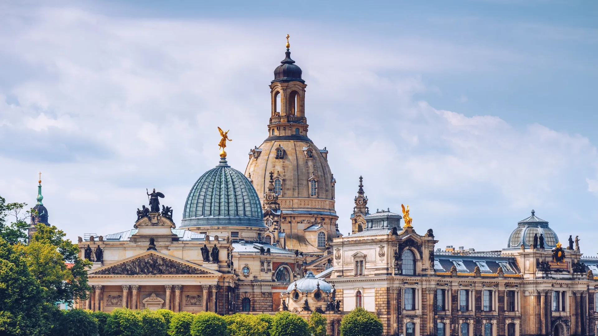 Historische Sandsteinbauten mit Kuppeln und Statuen in Dresden vor bewölktem Himmel.