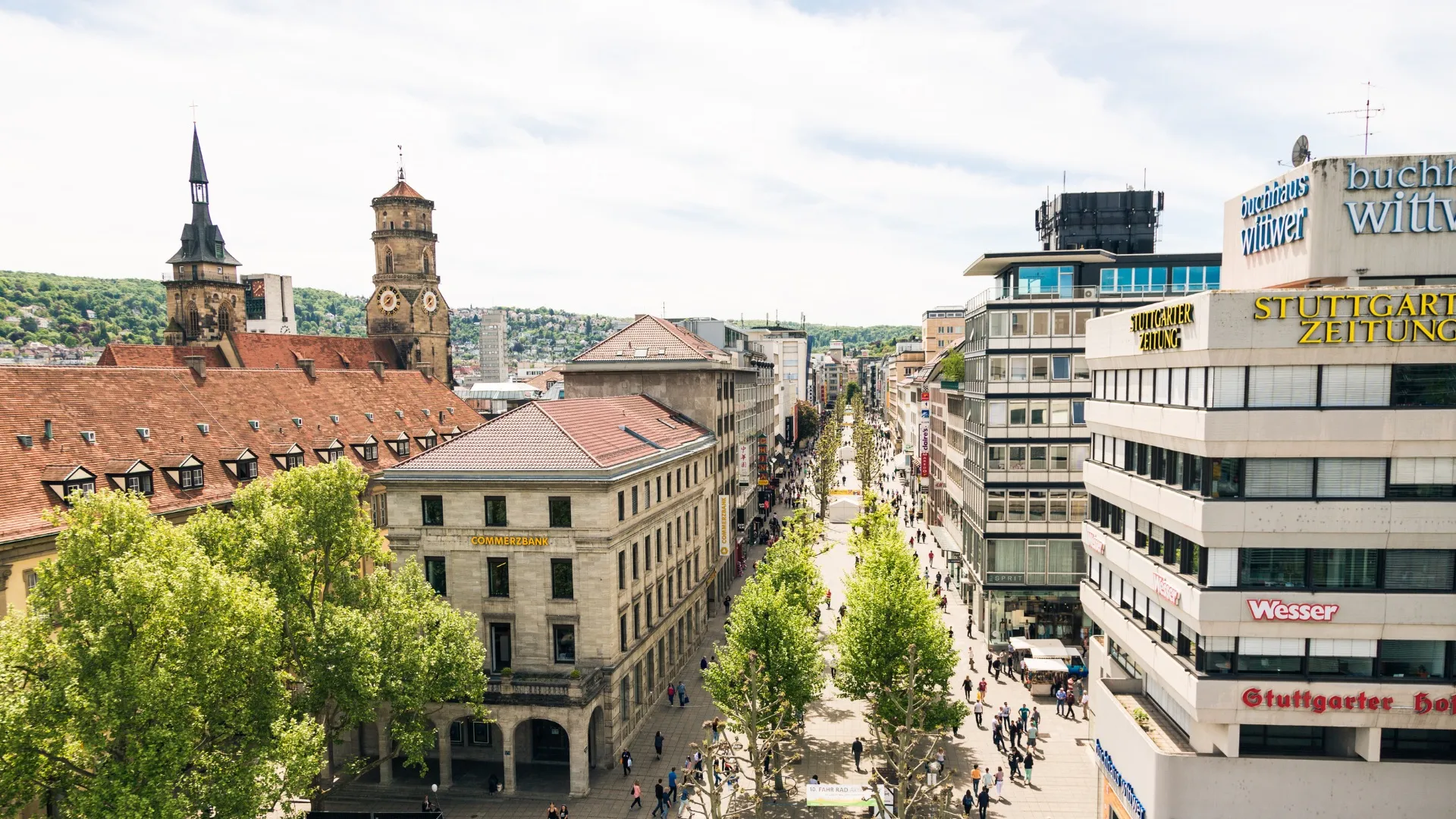Blick auf belebte Einkaufsstraße in Stuttgart mit historischen Gebäuden und moderner Architektur.