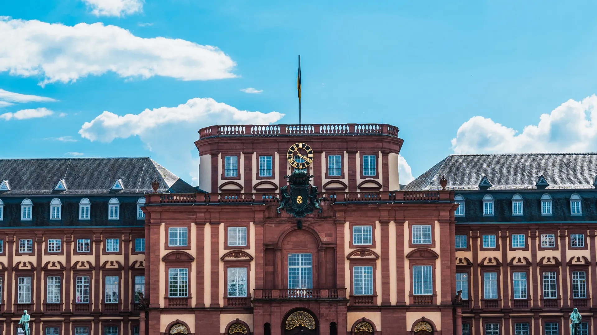 Schloss Mannheim mit Uhr und blauem Himmel im Hintergrund.