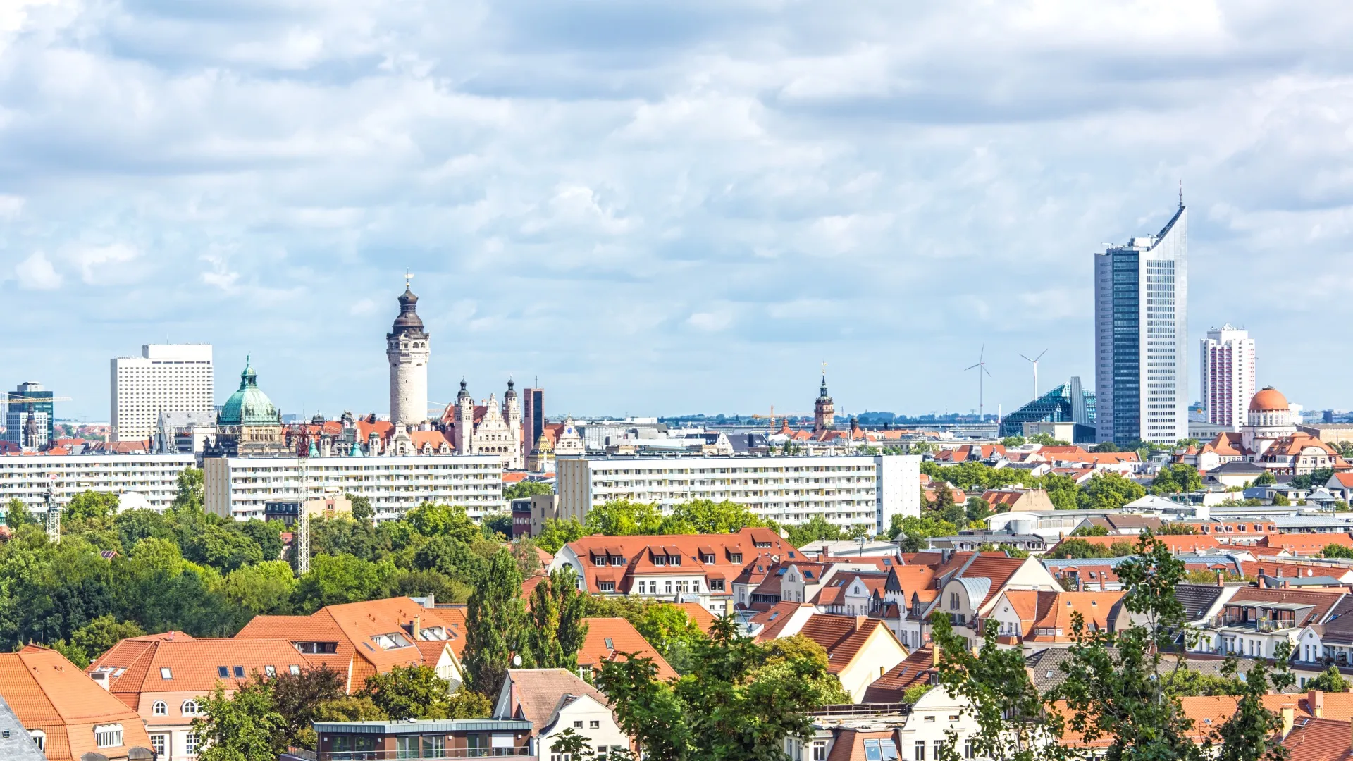 Stadtsilhouette von Leipzig mit modernen und historischen Gebäuden unter bewölktem Himmel.