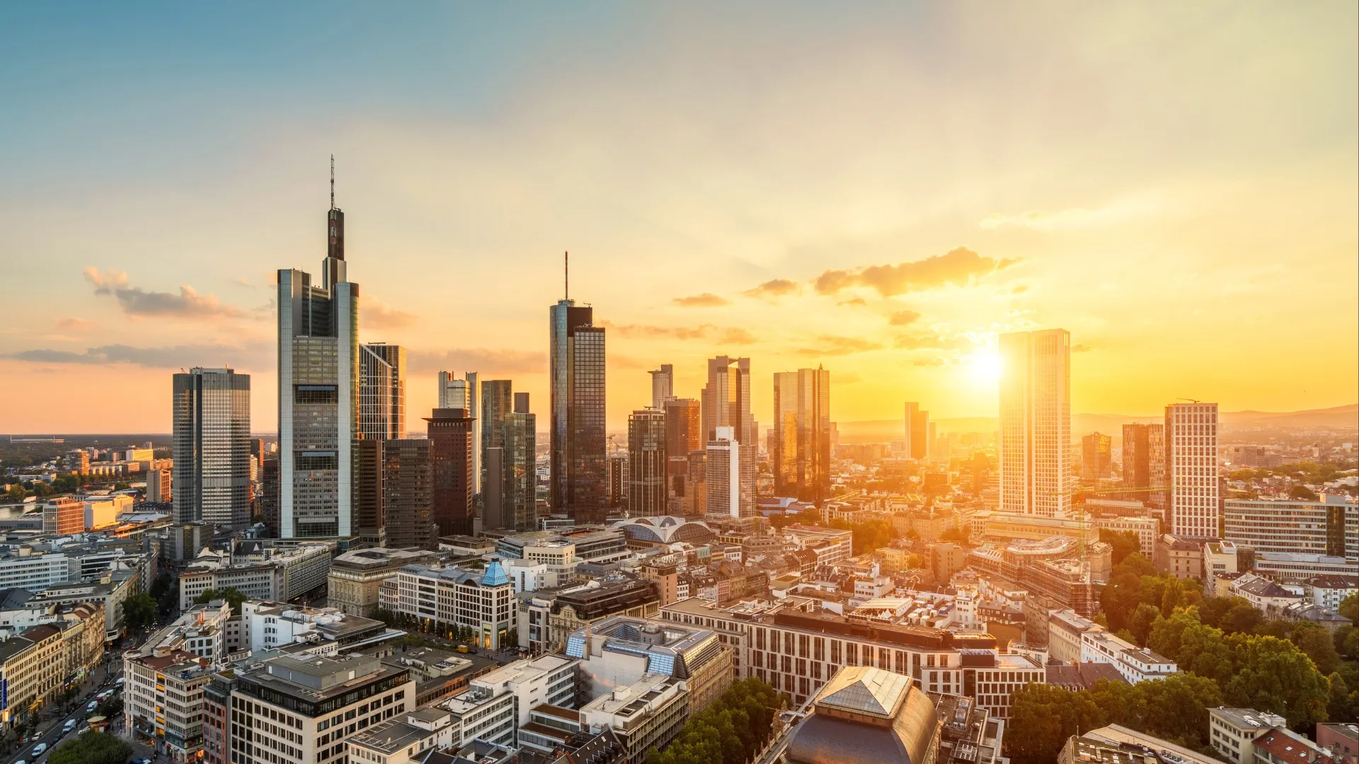 Frankfurts Skyline bei Sonnenuntergang mit Hochhäusern und goldenem Himmel.