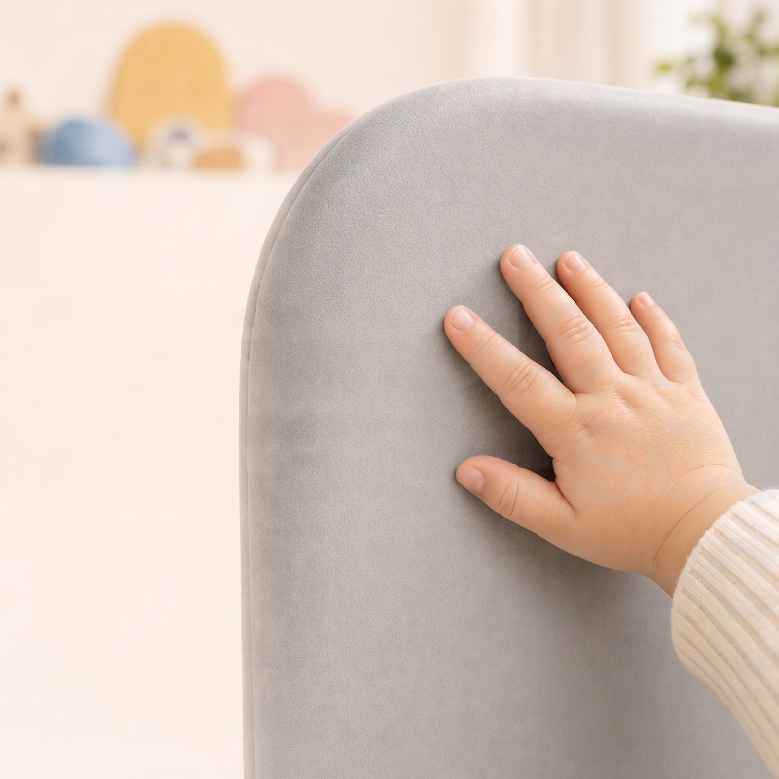 Eine Kinderhand liegt auf dem samtig-grauen Peachskin-Bezug des Bettgitters