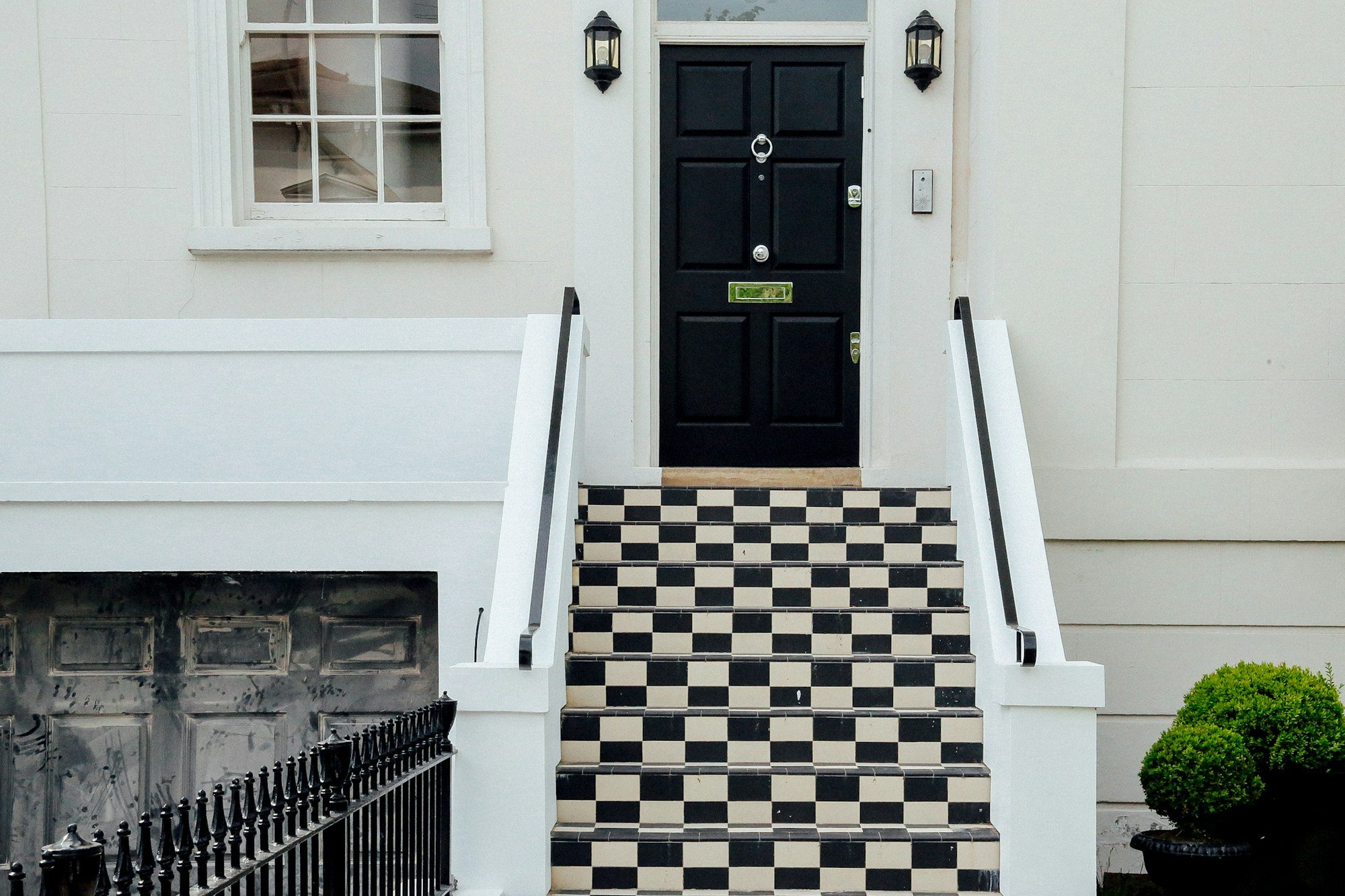 Black front door and chequered steps on a white stucco house