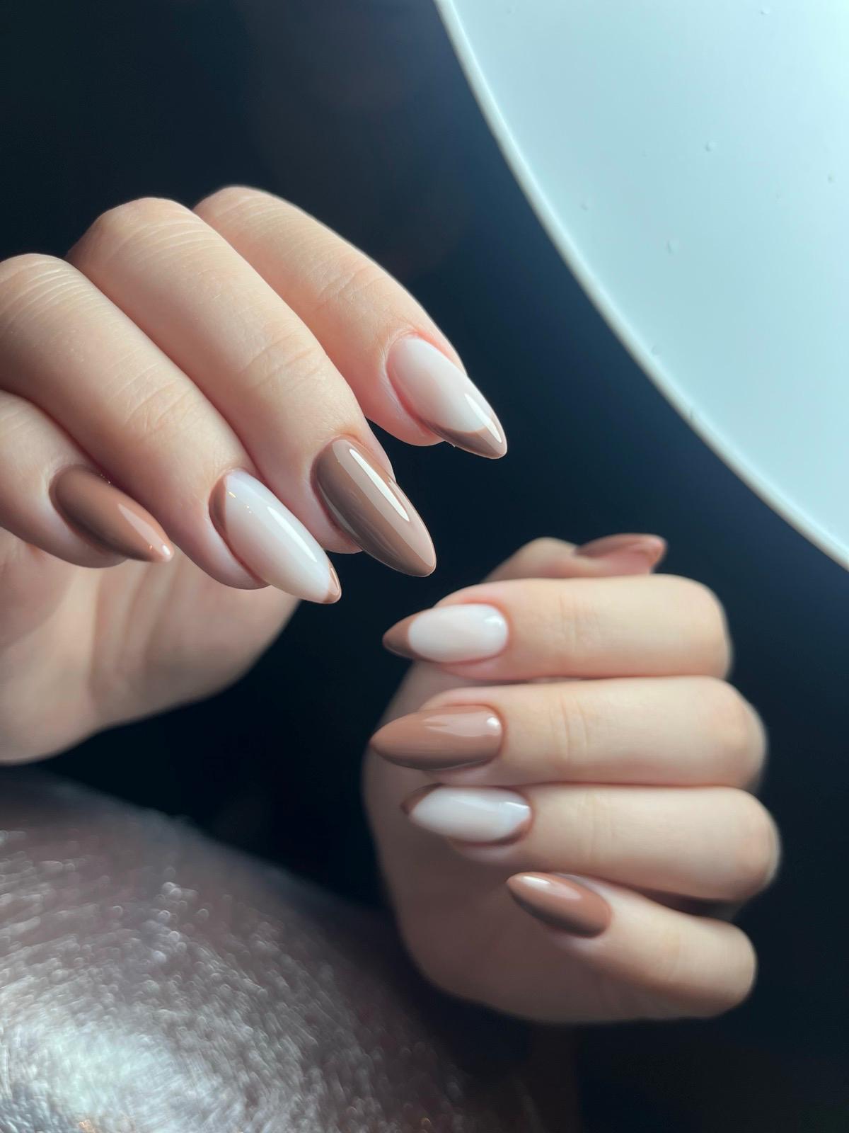 Handen met langwerpige nagels in beige en bruine tinten met een glanzende afwerking.