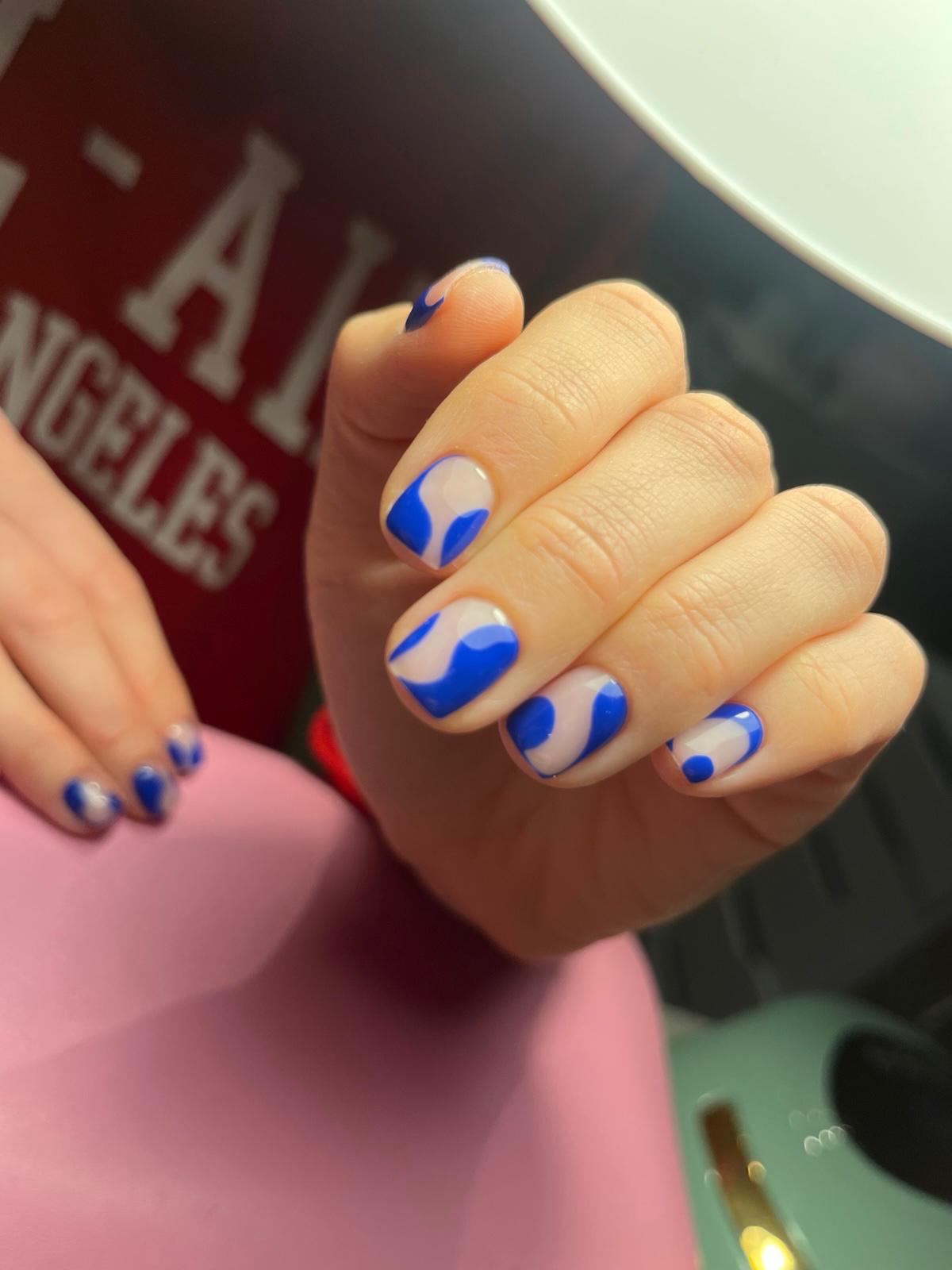 Hand met geel-witte madeliefjes nail art en een gouden ring met een diamanten steen.