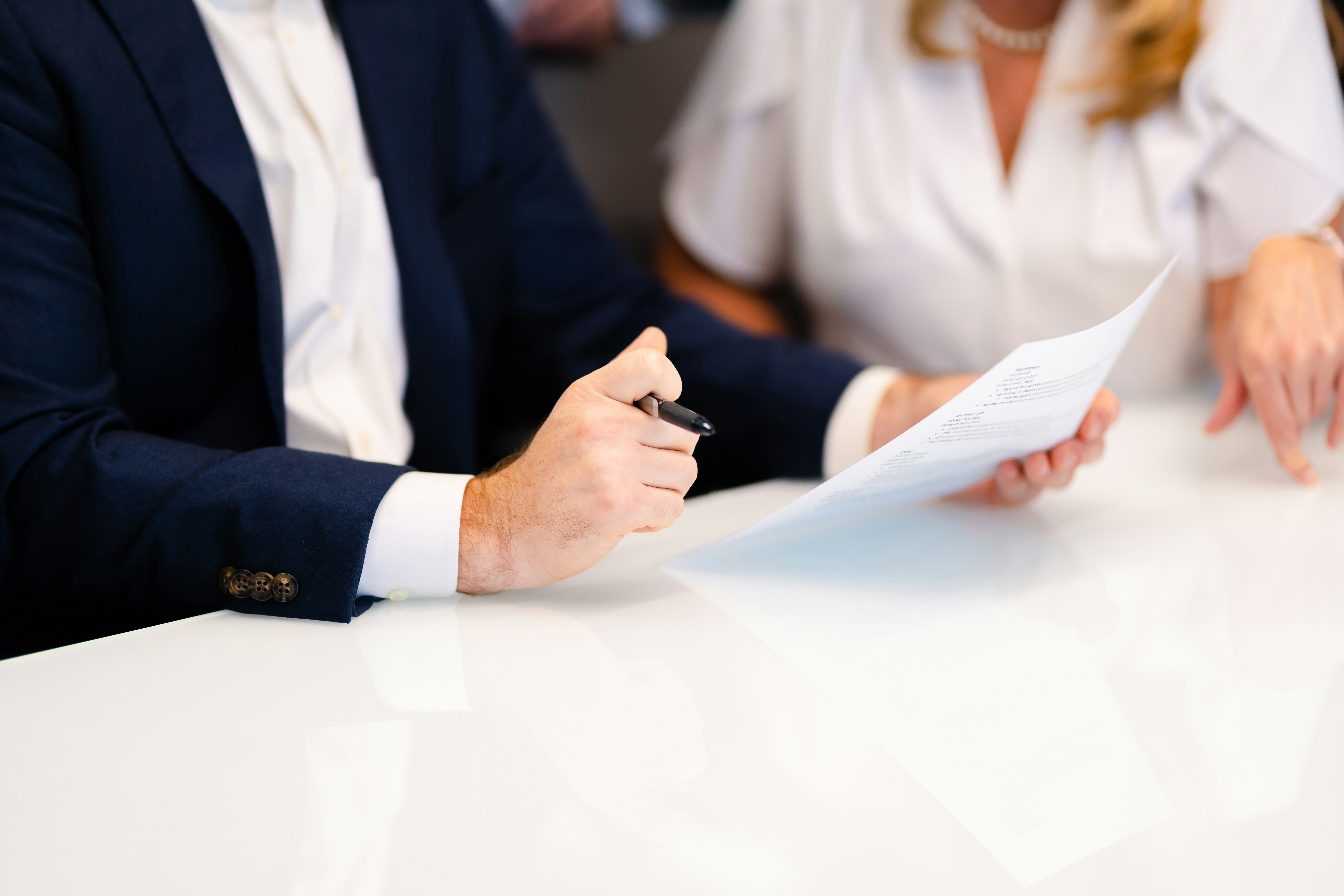 Two professionals reviewing a document together at a white desk.