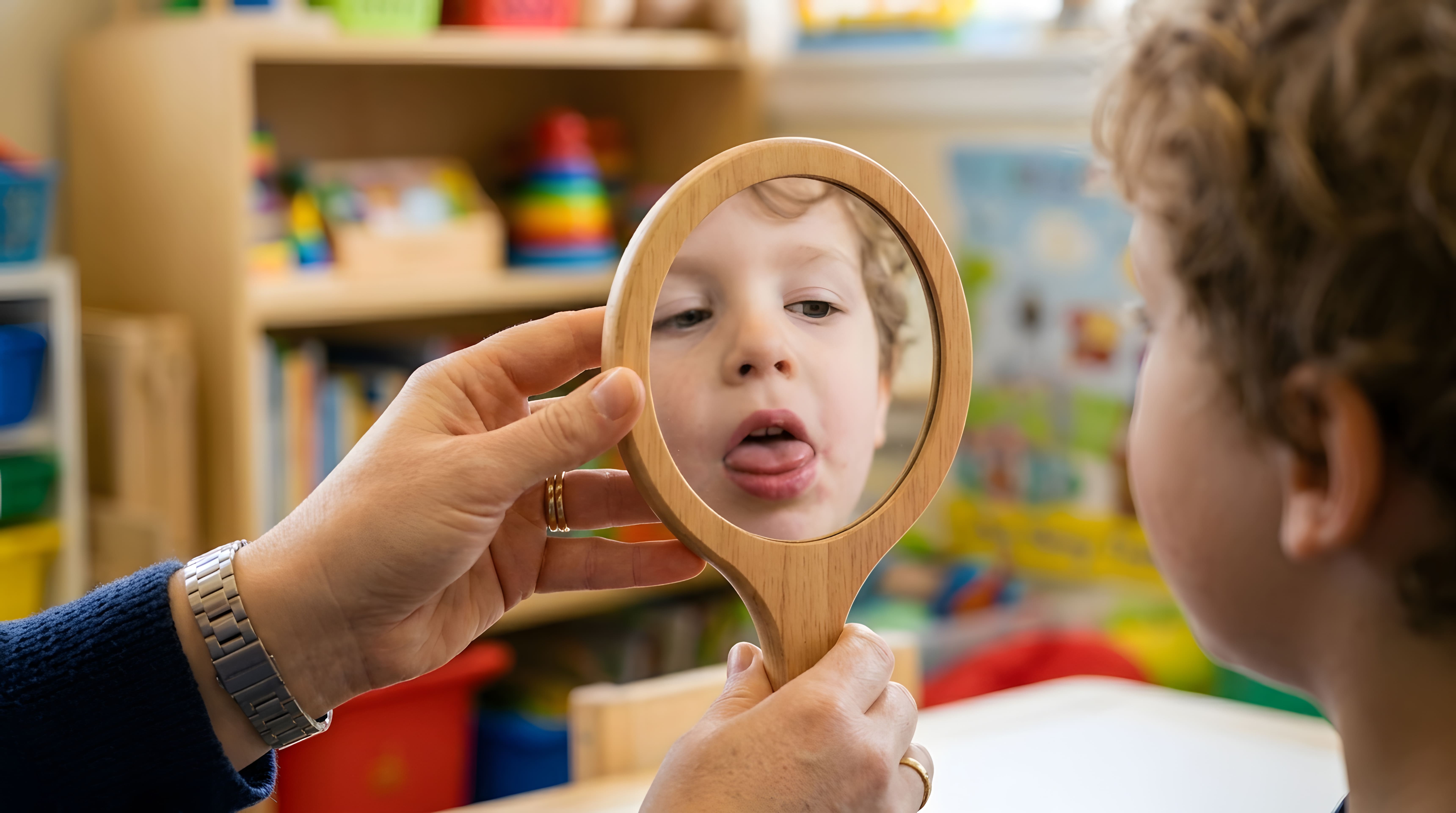 Child looking in a mirror and sticking out their tongue during a myofunctional oral habit evaluation