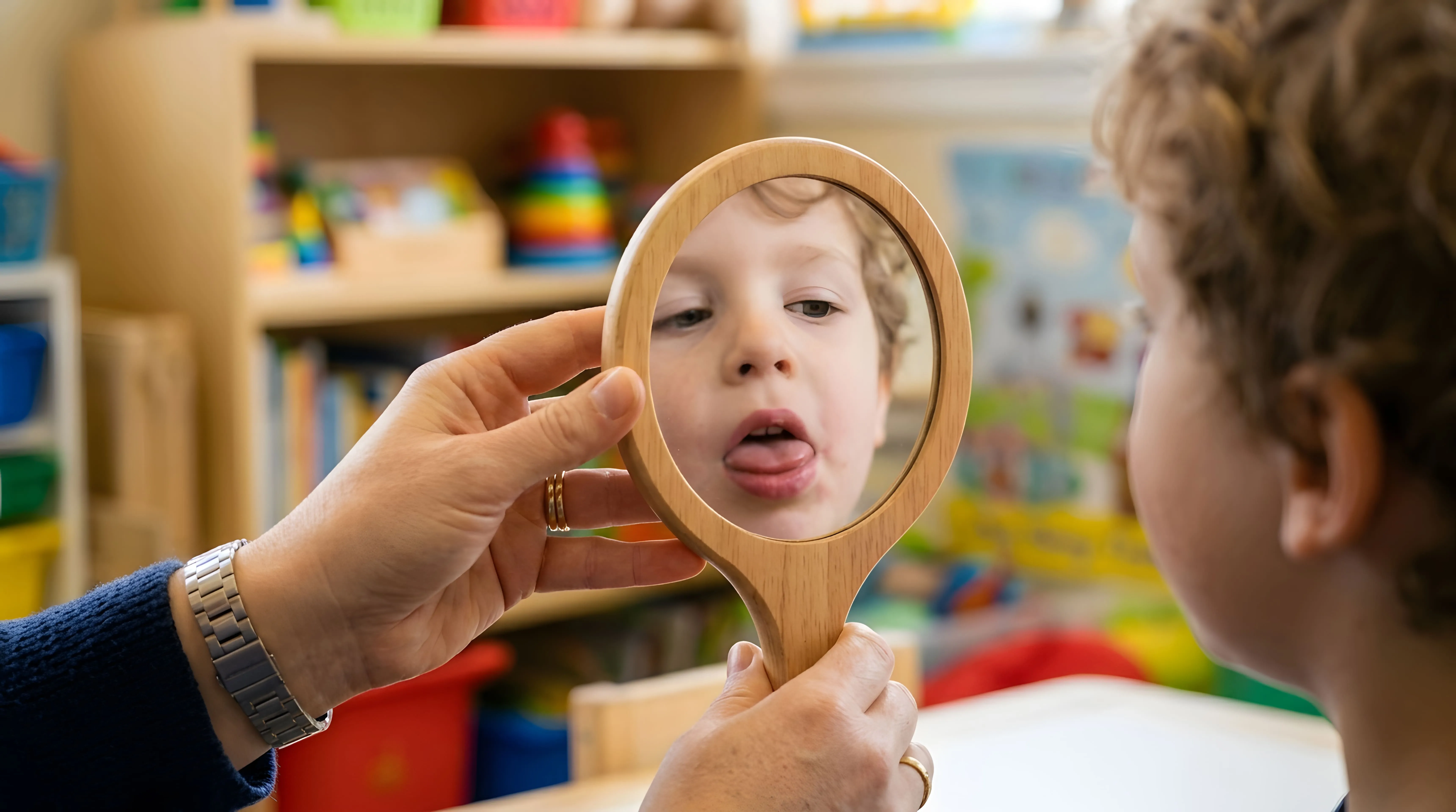 Child looking in a mirror and sticking out their tongue during a myofunctional oral habit evaluation