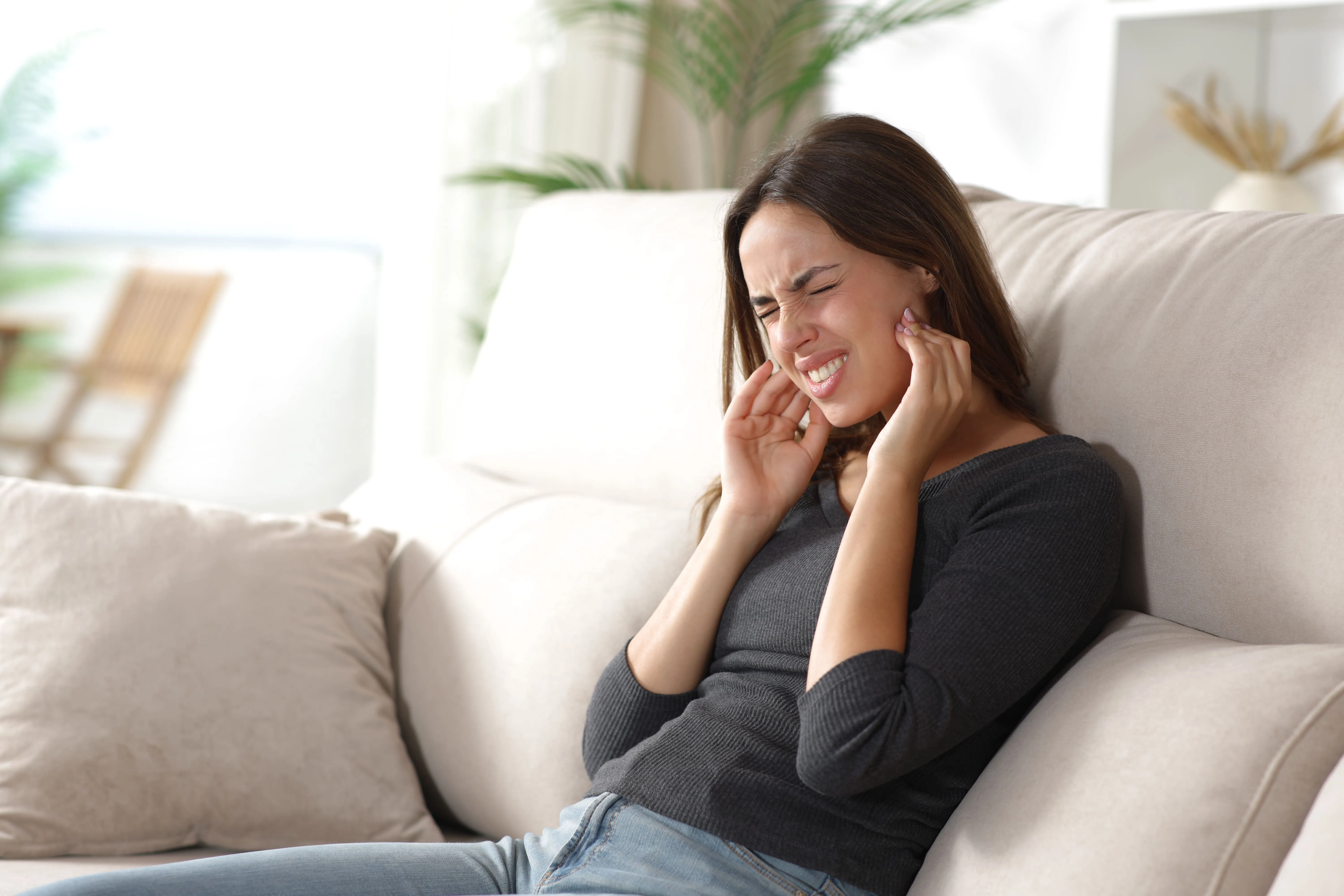 Patient holding her jaw because of TMJ pain