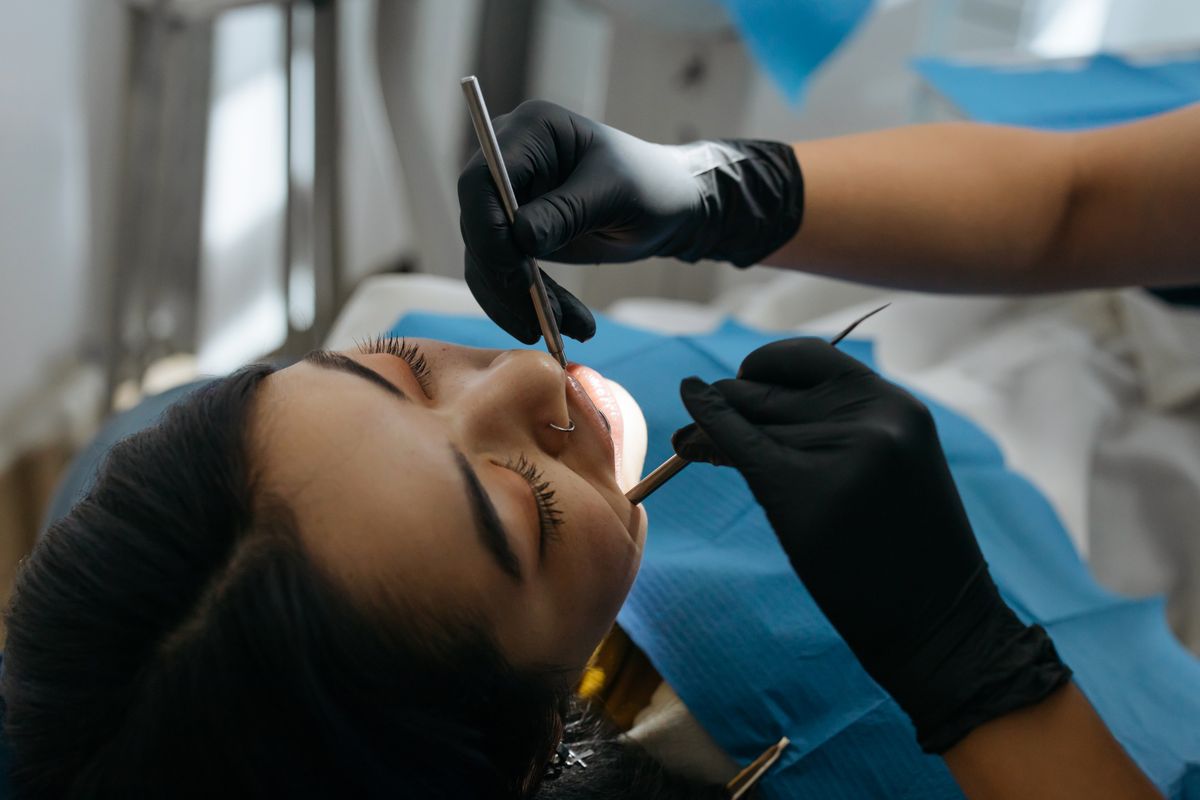 Dentist using dental instruments to examine a patient's lower jaw