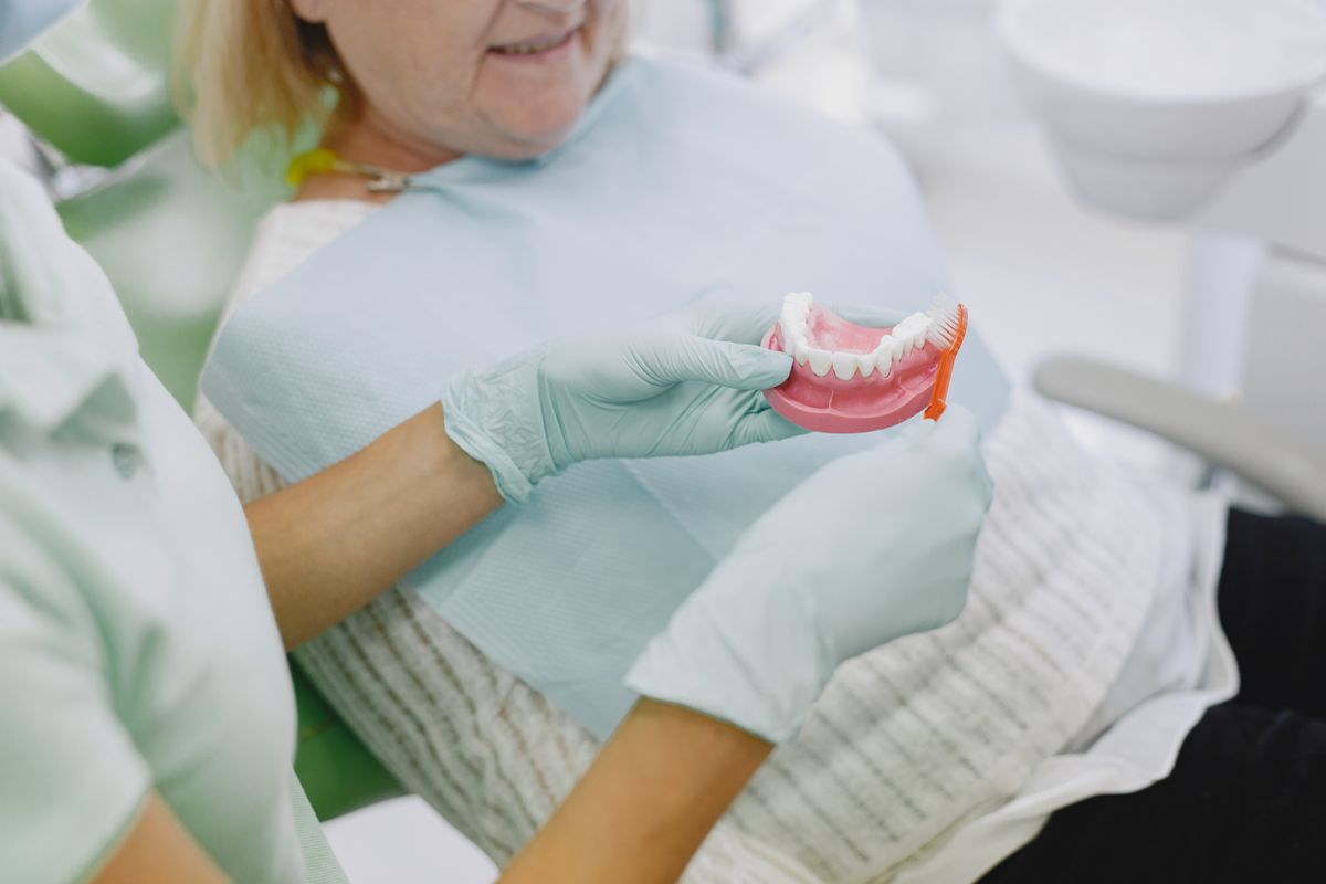 Dental professional showing a senior patient a denture model before tori removal